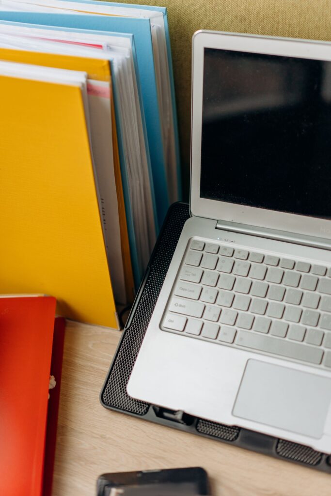 Laptop ao lado de pastas organizadas para preservar documentos de autoria